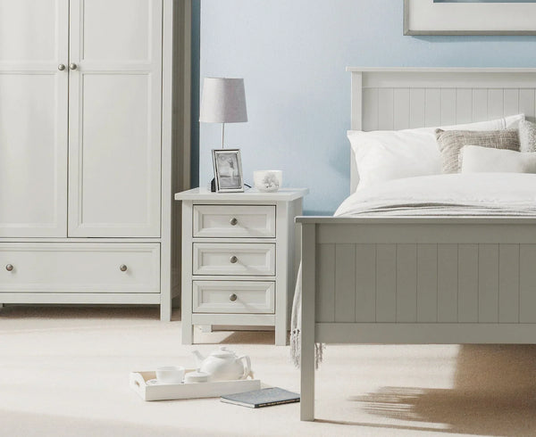 Dove grey 3 drawer bedside table beside matching bed with white bedding in styled bedroom