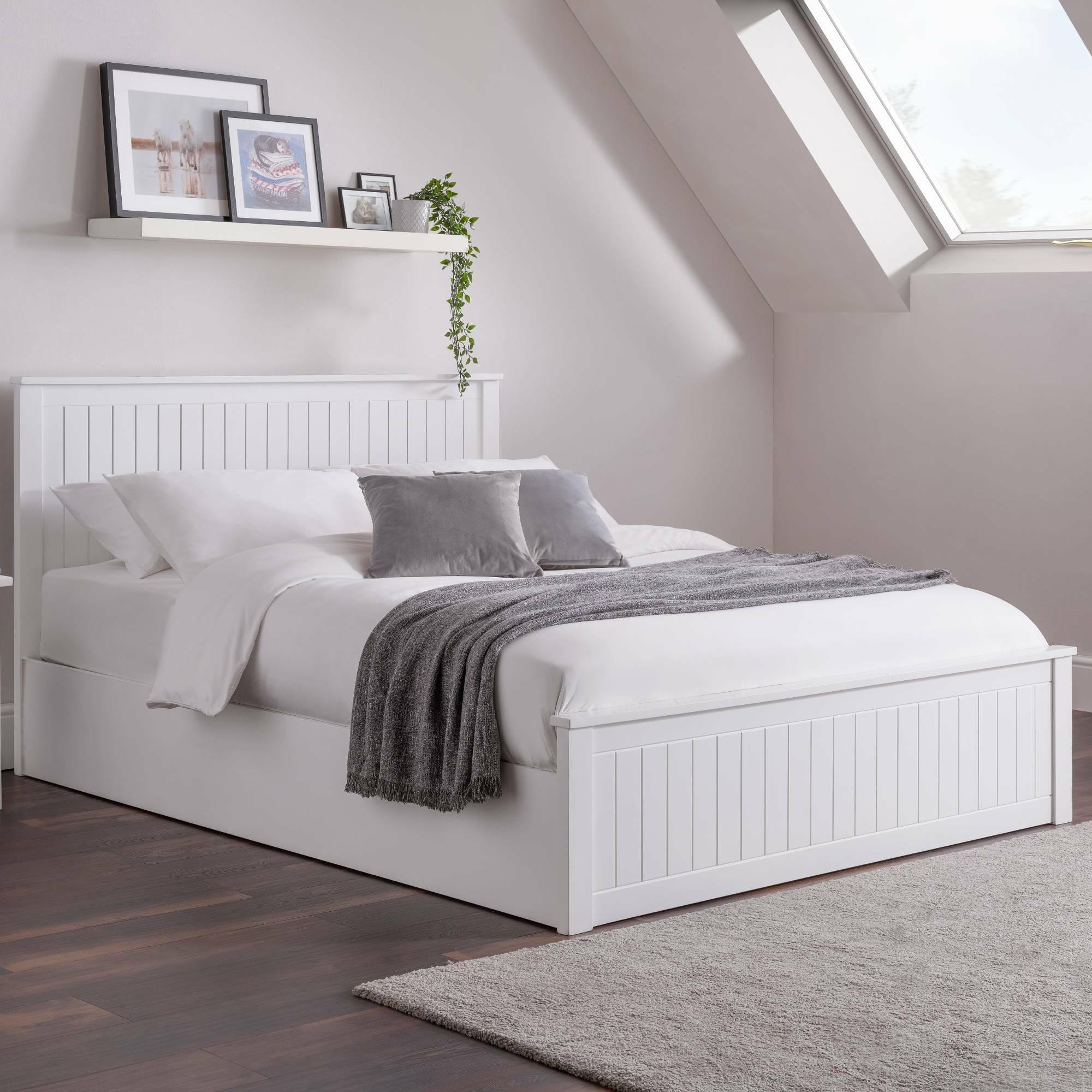White wooden bed frame with vertical panel design, grey throw and cushions, in modern bedroom