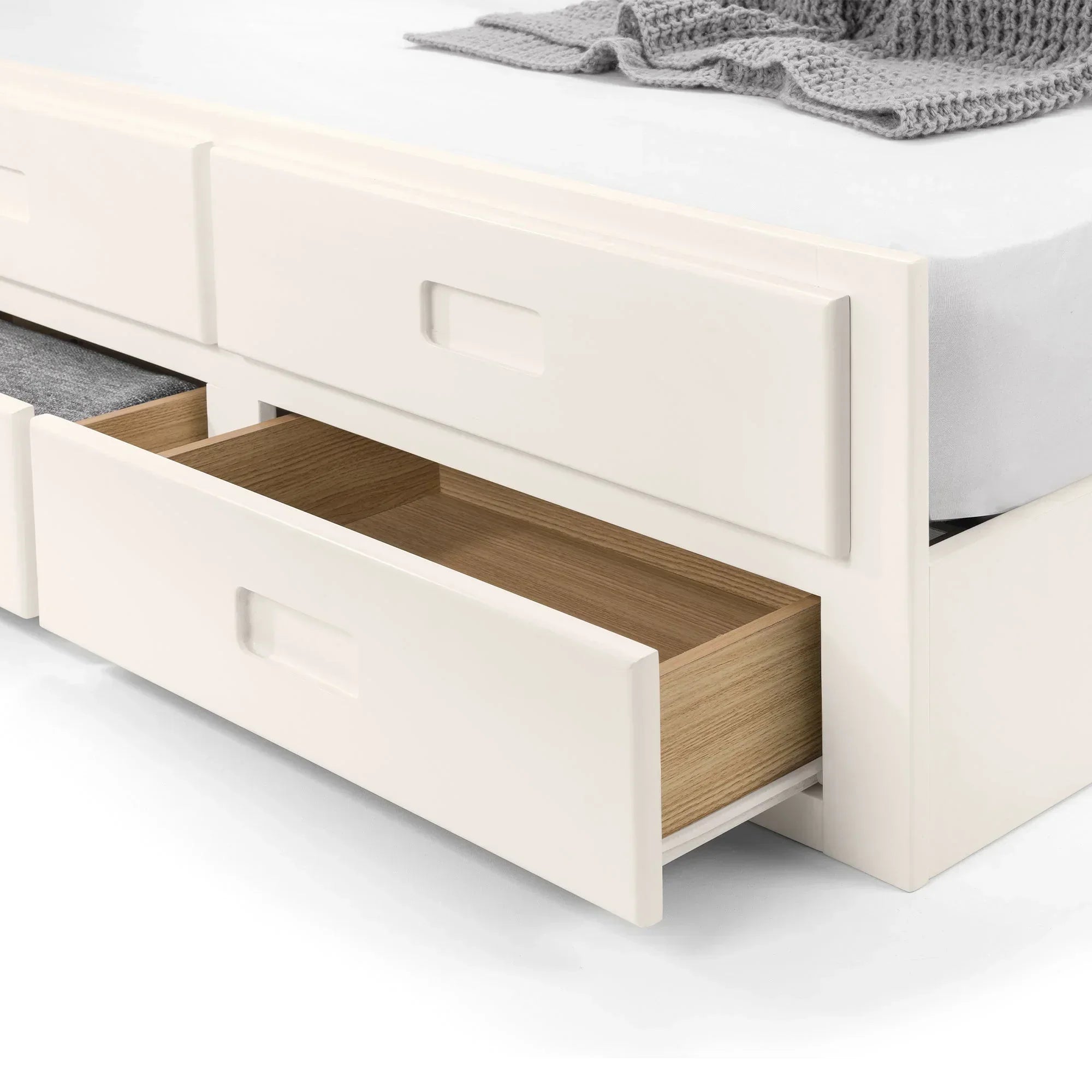 White single daybed with mattress, open storage drawers, wood and fabric detail visible