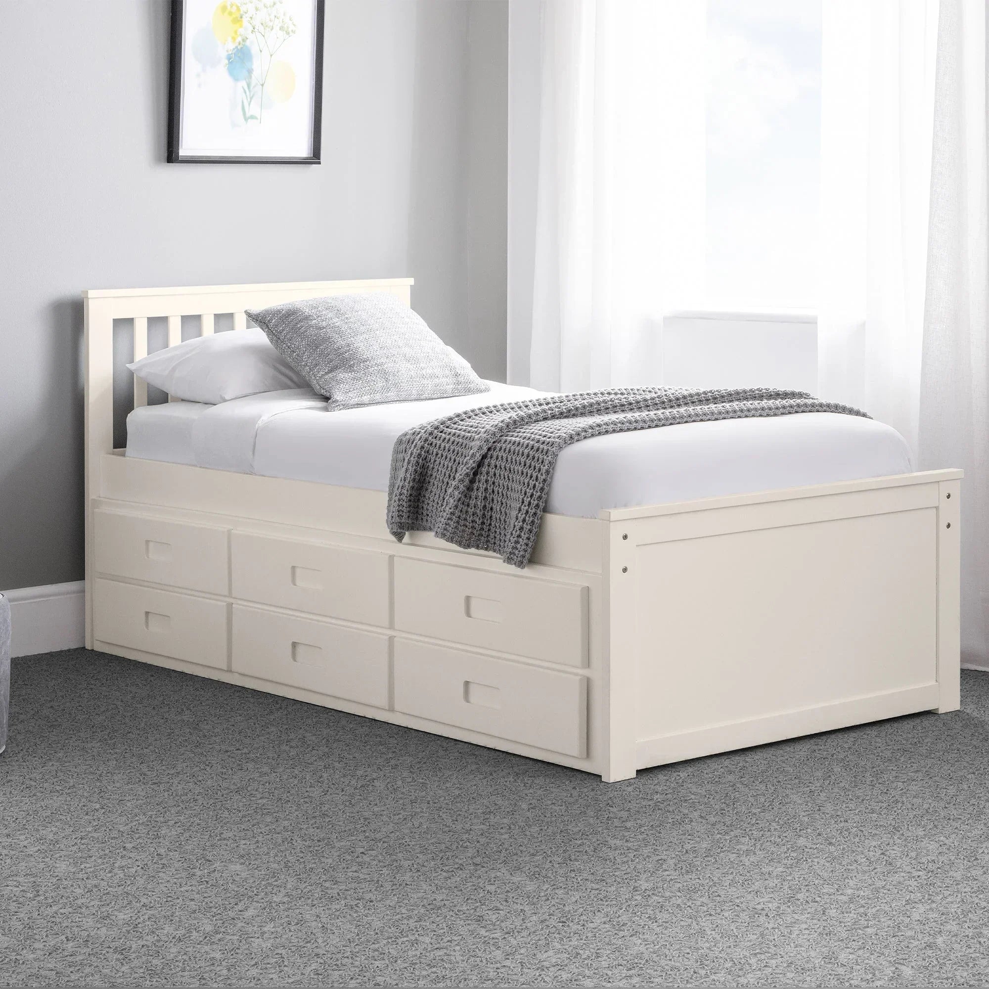 White single daybed with storage drawers, grey blanket, and pillow in bright bedroom