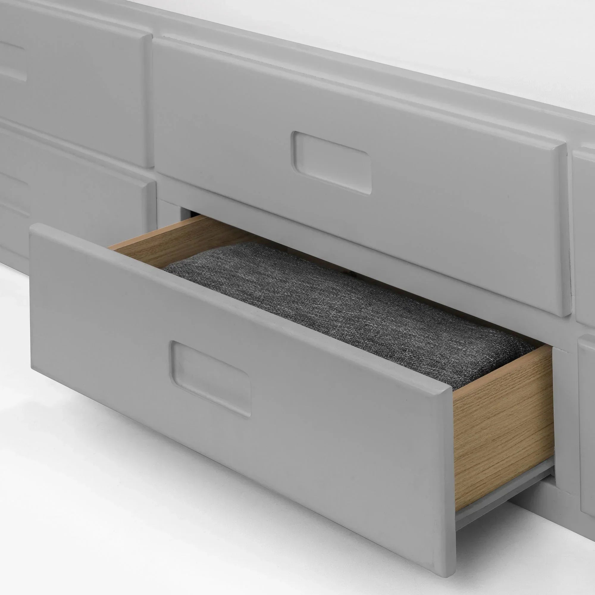 Light grey daybed storage drawer partially open with folded blanket inside