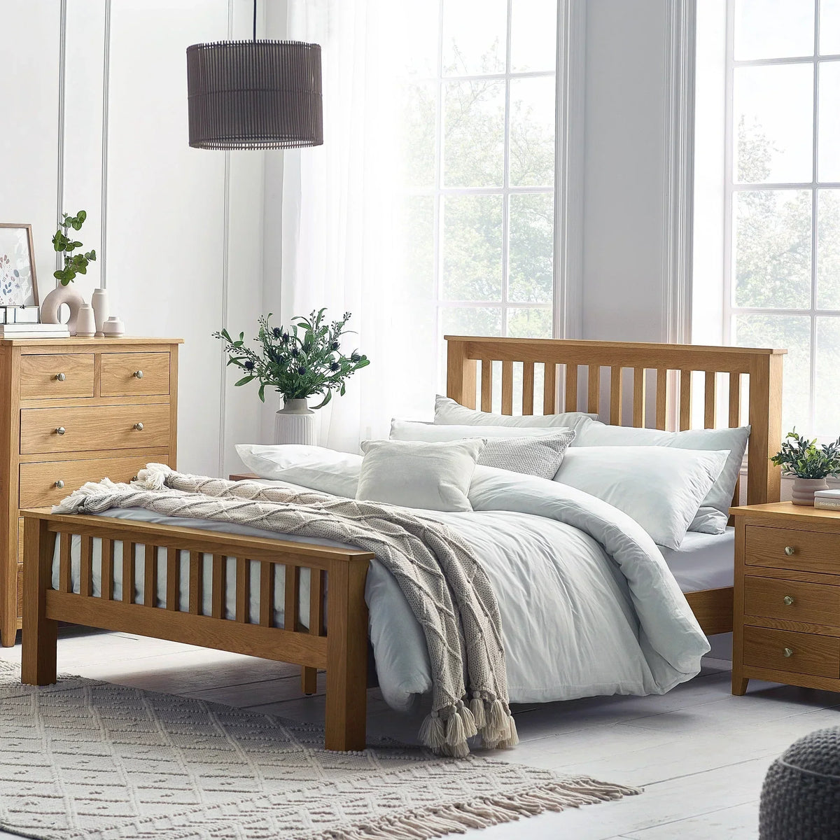 Oak double bed with slatted headboard in bright bedroom, matching nightstand and chest