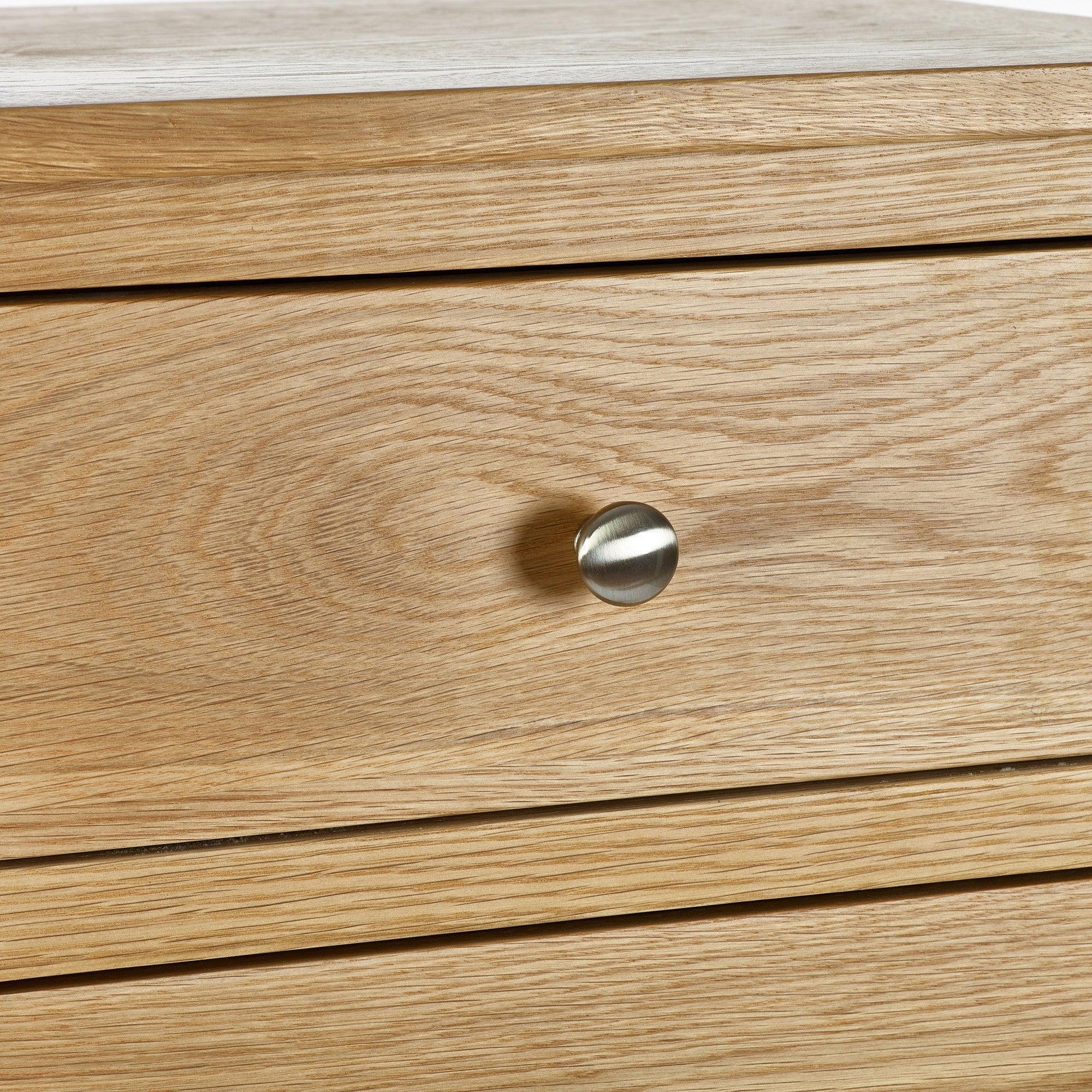 Close-up of oak bedside table drawer with brushed metal knob handle