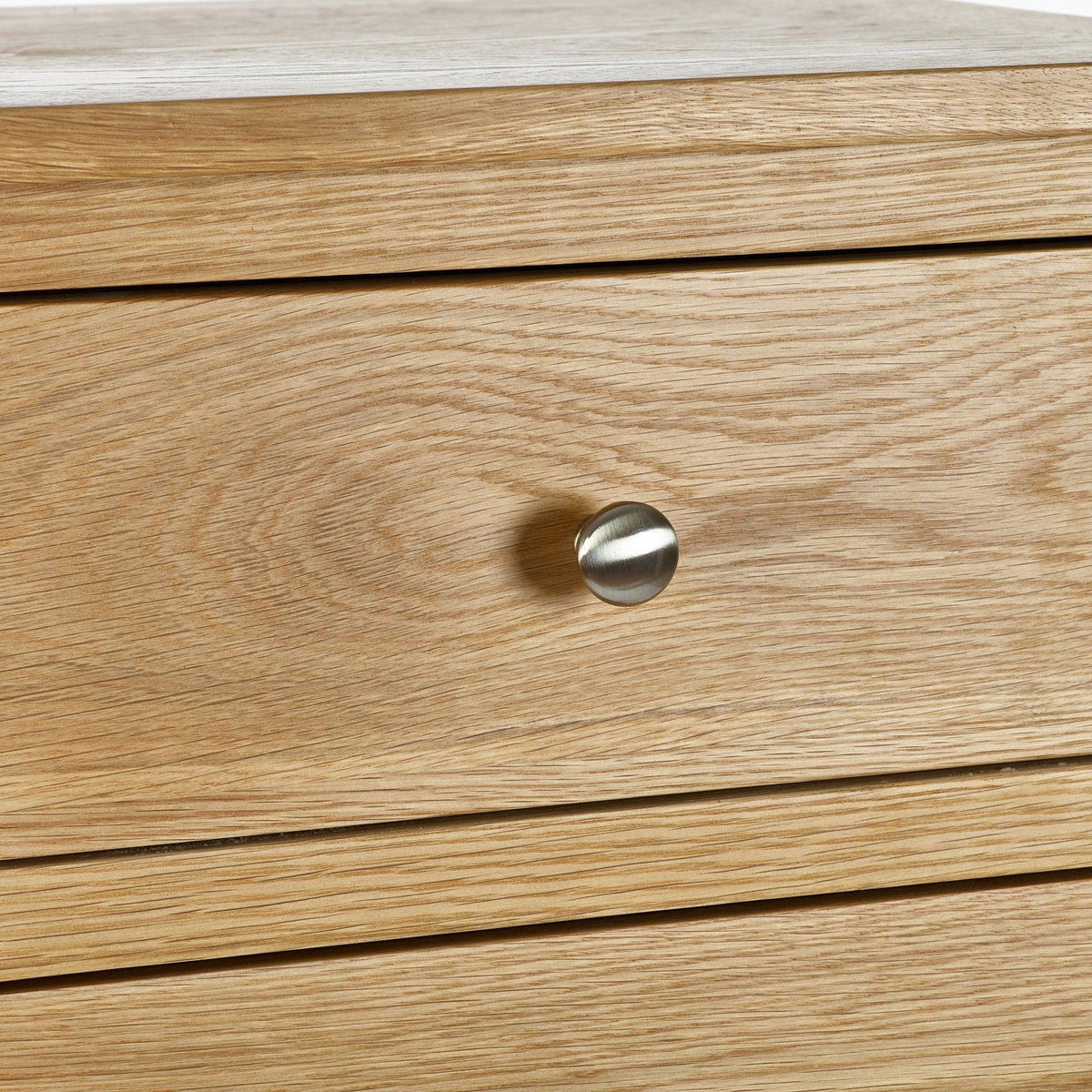 Close-up of oak bedside table drawer with brushed metal knob handle