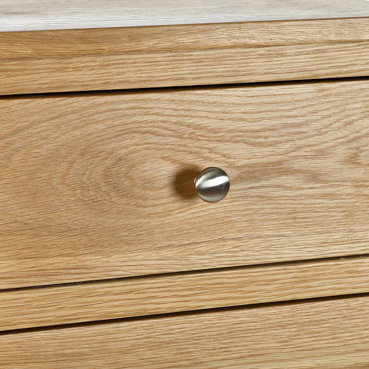 Oak chest of drawers close-up showing wood grain and round metal handle