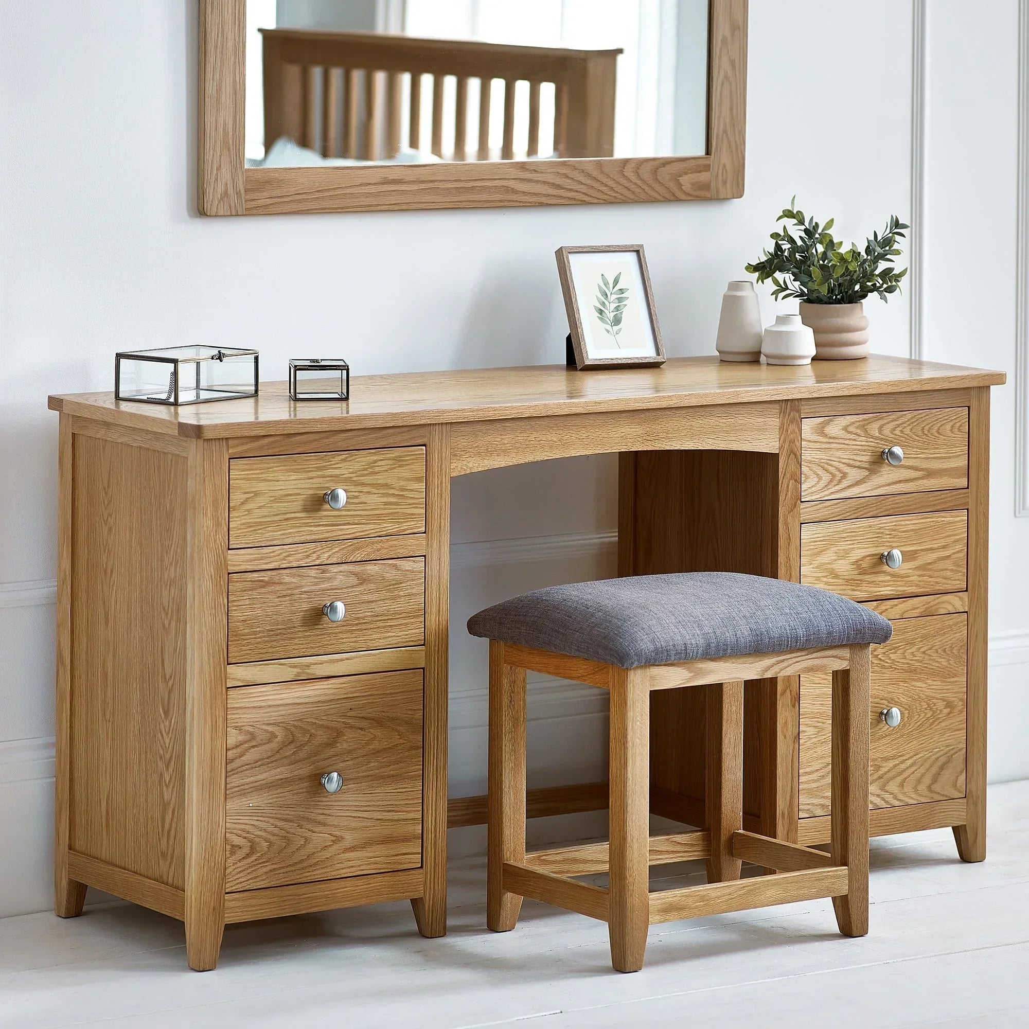 Oak twin dressing table with six drawers and grey cushioned stool in bright bedroom