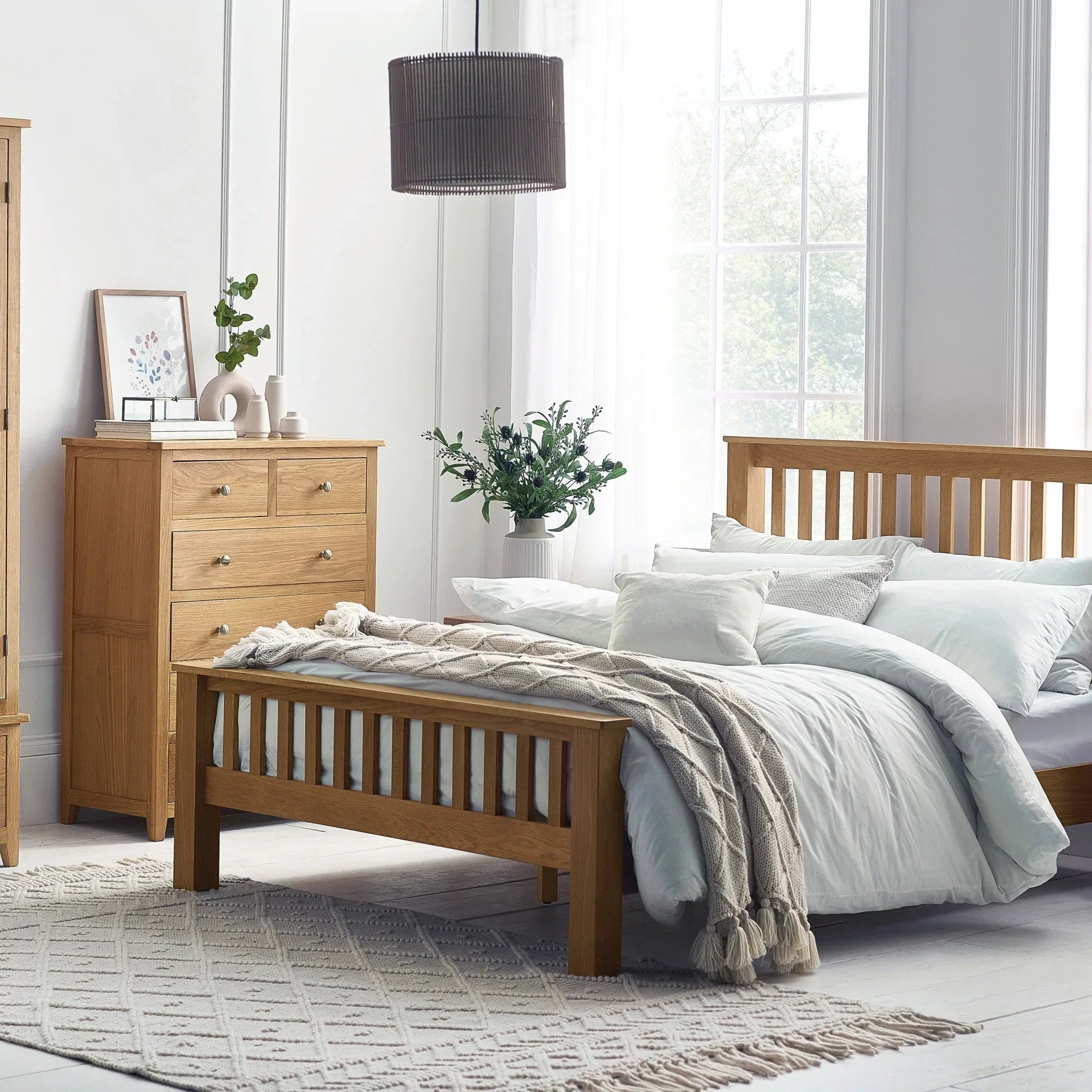 Oak combination wardrobe with matching bed and drawers in a bright bedroom setting