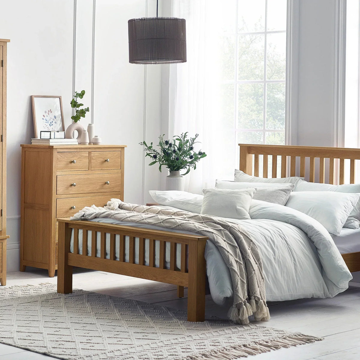 Oak combination wardrobe with matching bed and drawers in a bright bedroom setting