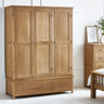 Oak 3 door wardrobe with panelled doors and two drawers in a bright bedroom