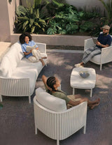 Image of White 5 seater outdoor lounging set with 3 people relaxing and reading