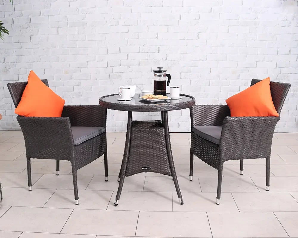 Rattan garden bistro set with two chairs, orange cushions, and round table on patio floor