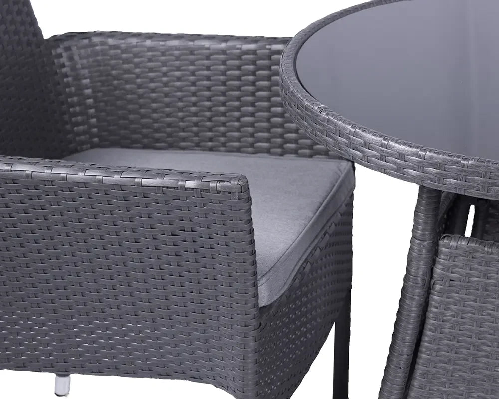 Grey rattan garden chair with cushion beside round glass-topped outdoor dining table
