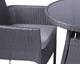 Grey rattan garden chair with cushion beside round glass-topped outdoor dining table