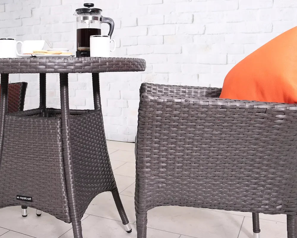 Brown rattan garden dining table set with chair, orange cushion, coffee cups and French press