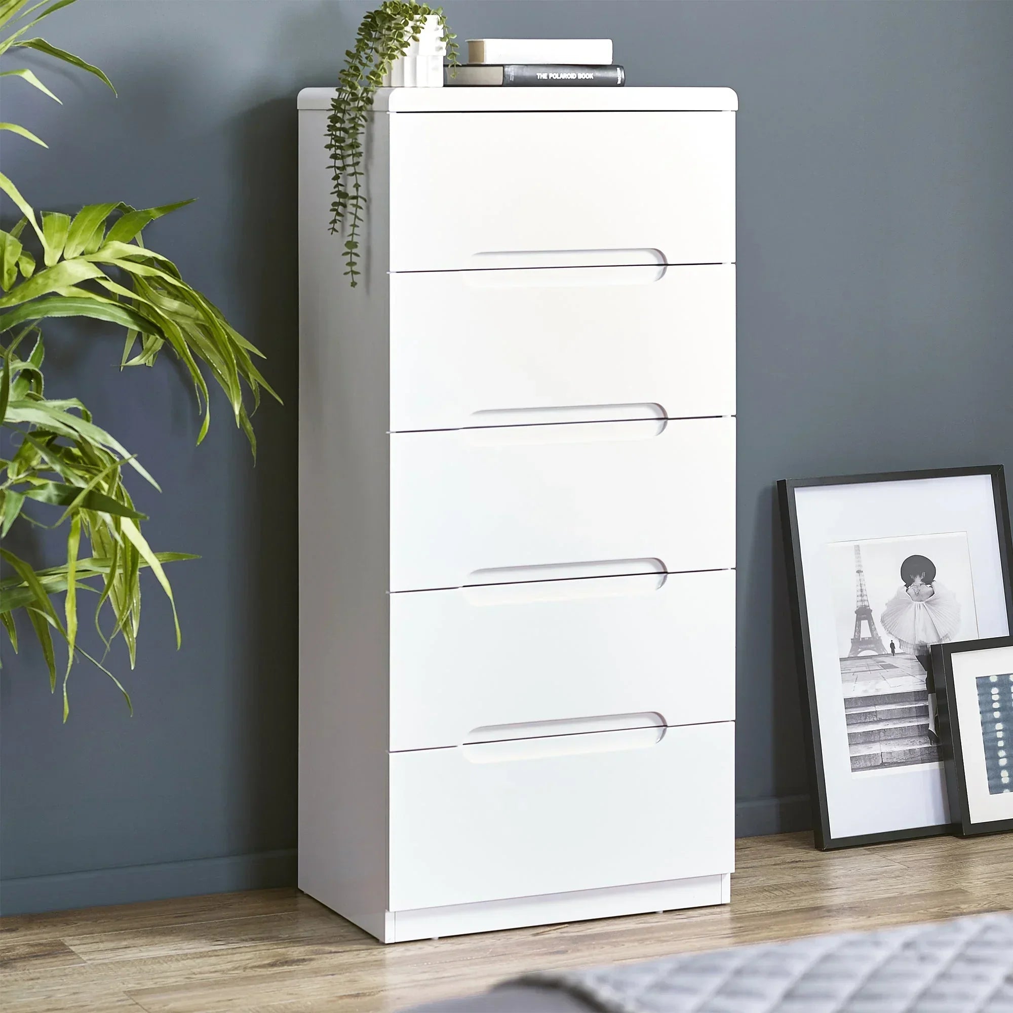White 5 drawer chest with sleek handles in modern bedroom setting on wooden floor