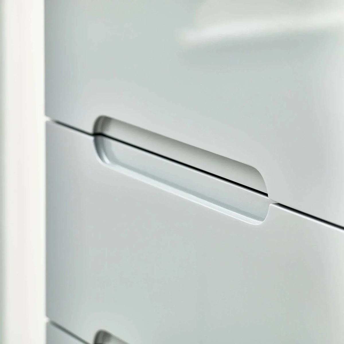 Grey narrow chest of drawers with integrated handle detail, modern bedroom furniture closeup
