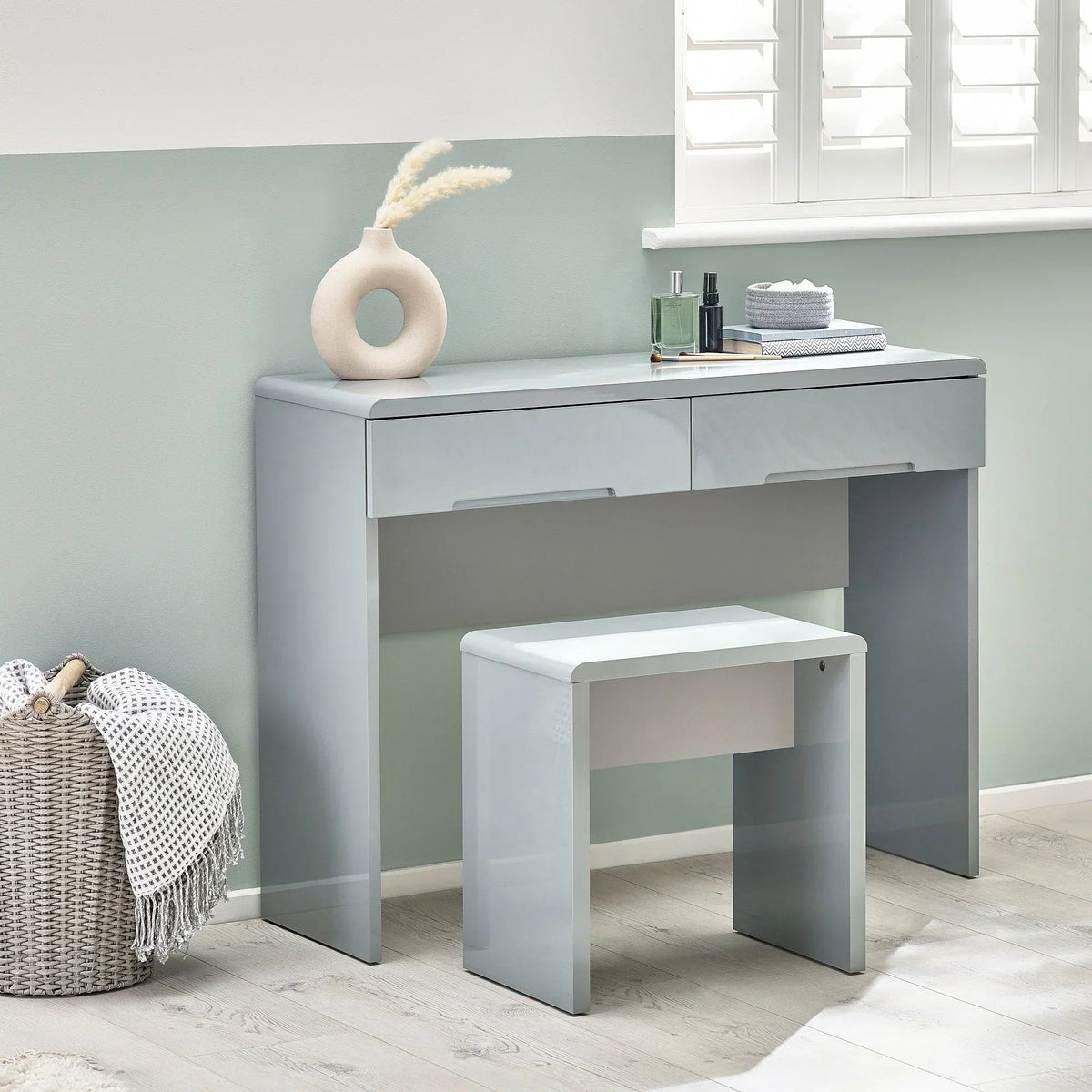 Grey dressing stool and matching dressing table with accessories in a bright modern room