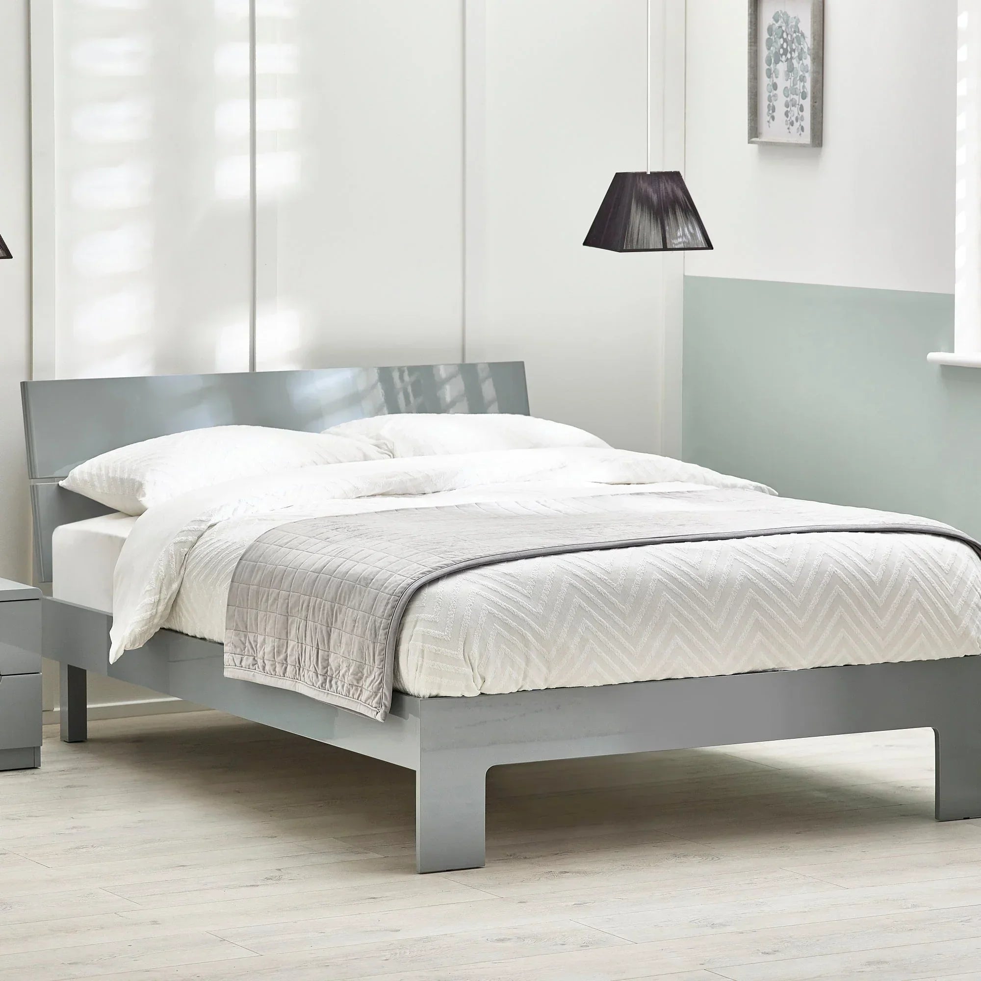 Grey double bed with high gloss frame, white bedding, in modern bright bedroom