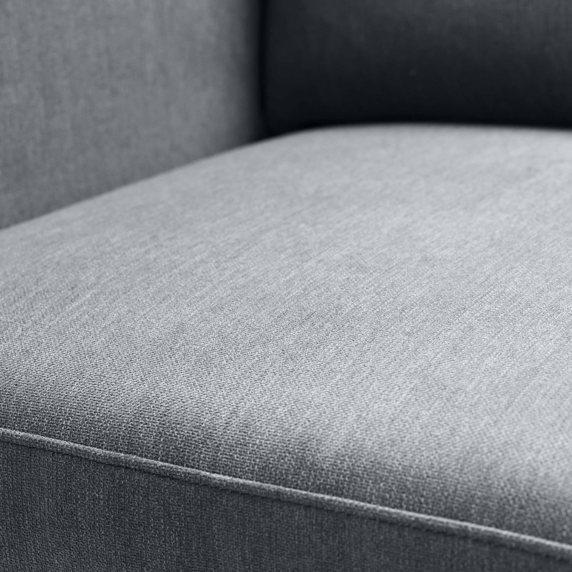 Close-up of grey corner sofa cushion with fabric upholstery and stitched seam detail