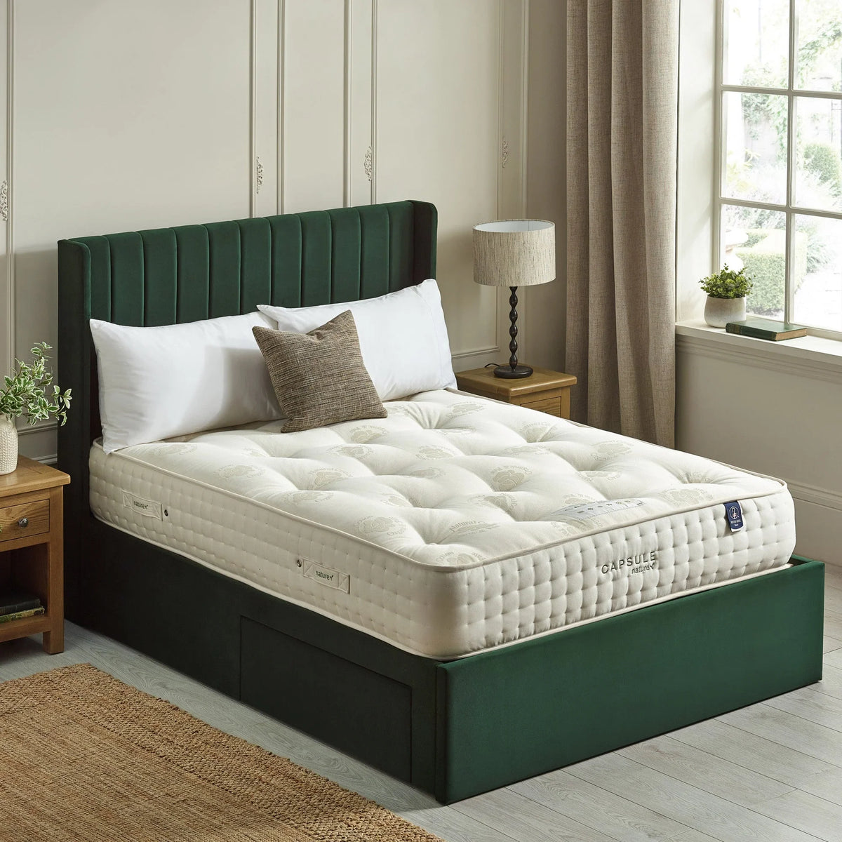 Luxury pocket sprung mattress on green upholstered bed frame beside wooden nightstands
