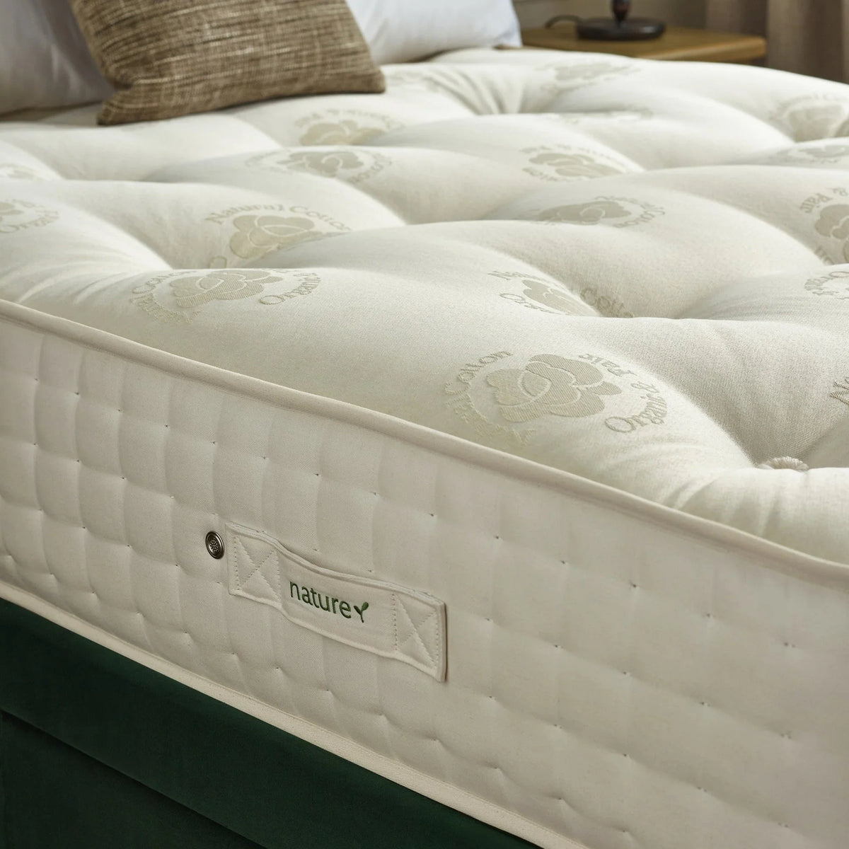 Natural cotton mattress with quilted sides and label on upholstered bed base