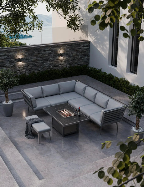 Grey outdoor corner sofa set with fire pit table on modern patio overlooking water