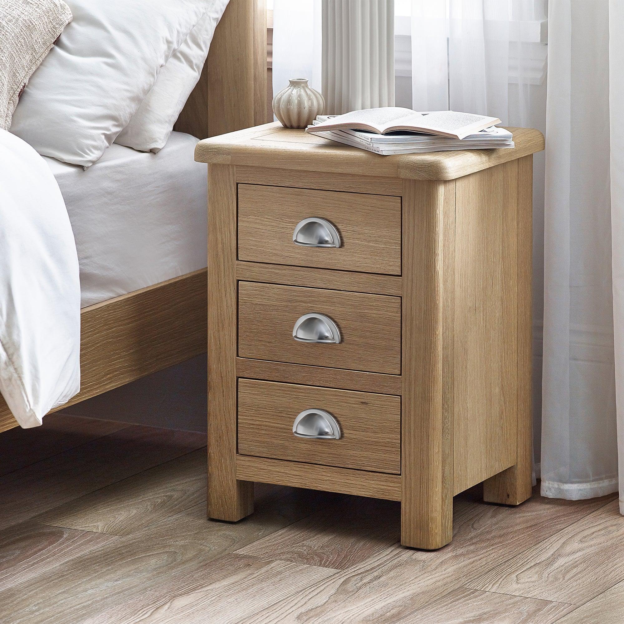 Memphis limed oak 3 drawer bedside table with silver handles beside bed in bright room