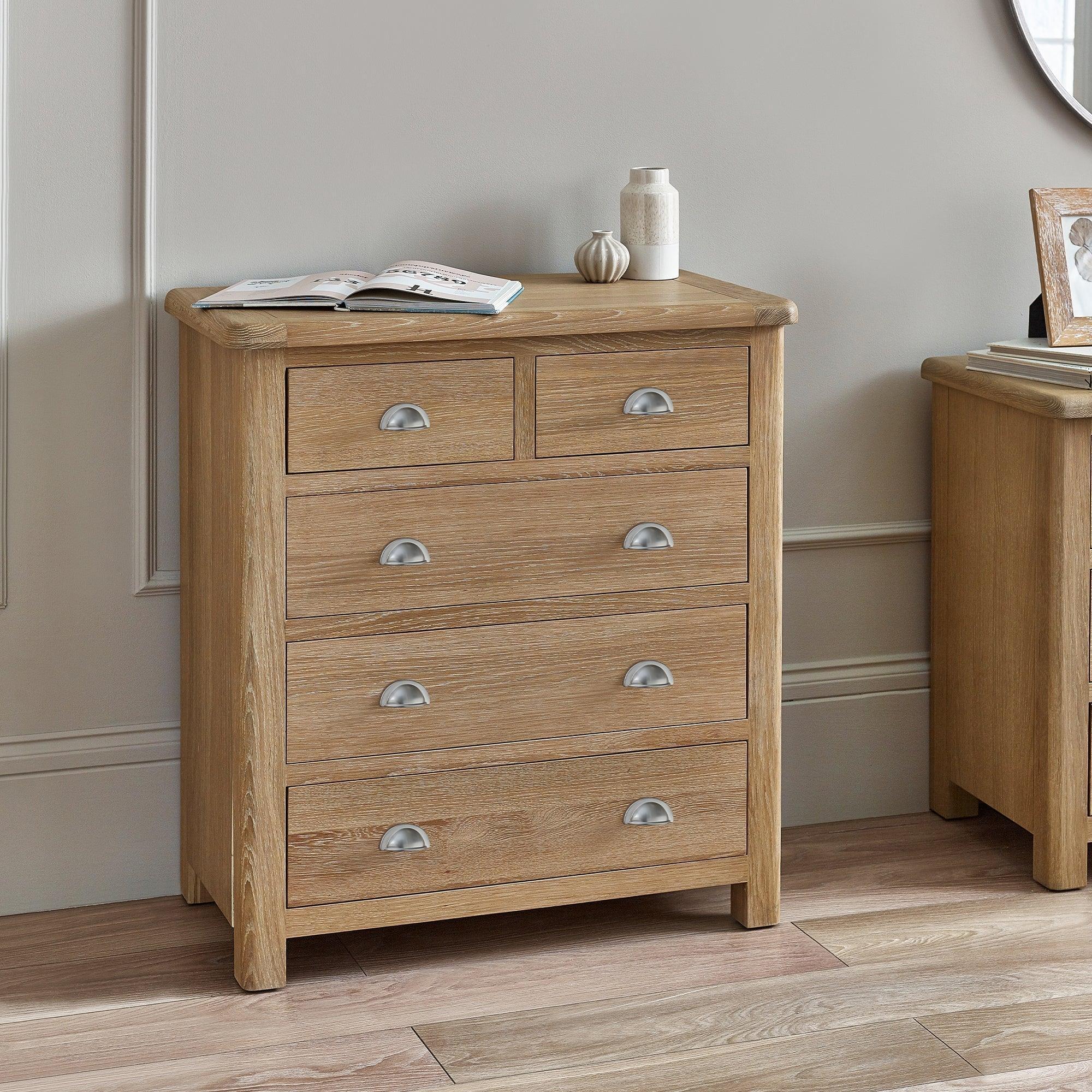 Memphis limed oak chest of drawers with metal cup handles in a modern bedroom