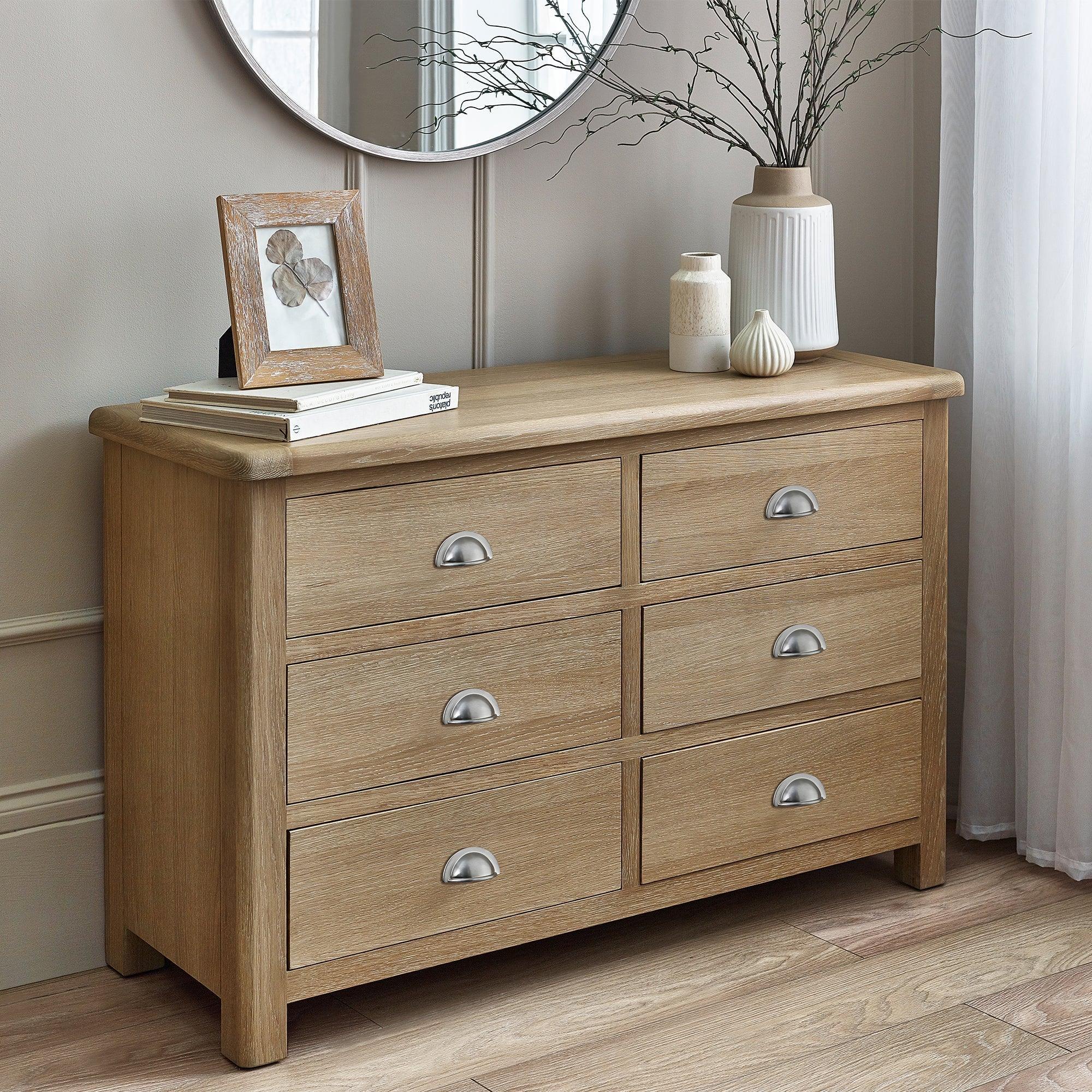 Limed oak 6 drawer wide chest with metal handles styled in a modern bedroom