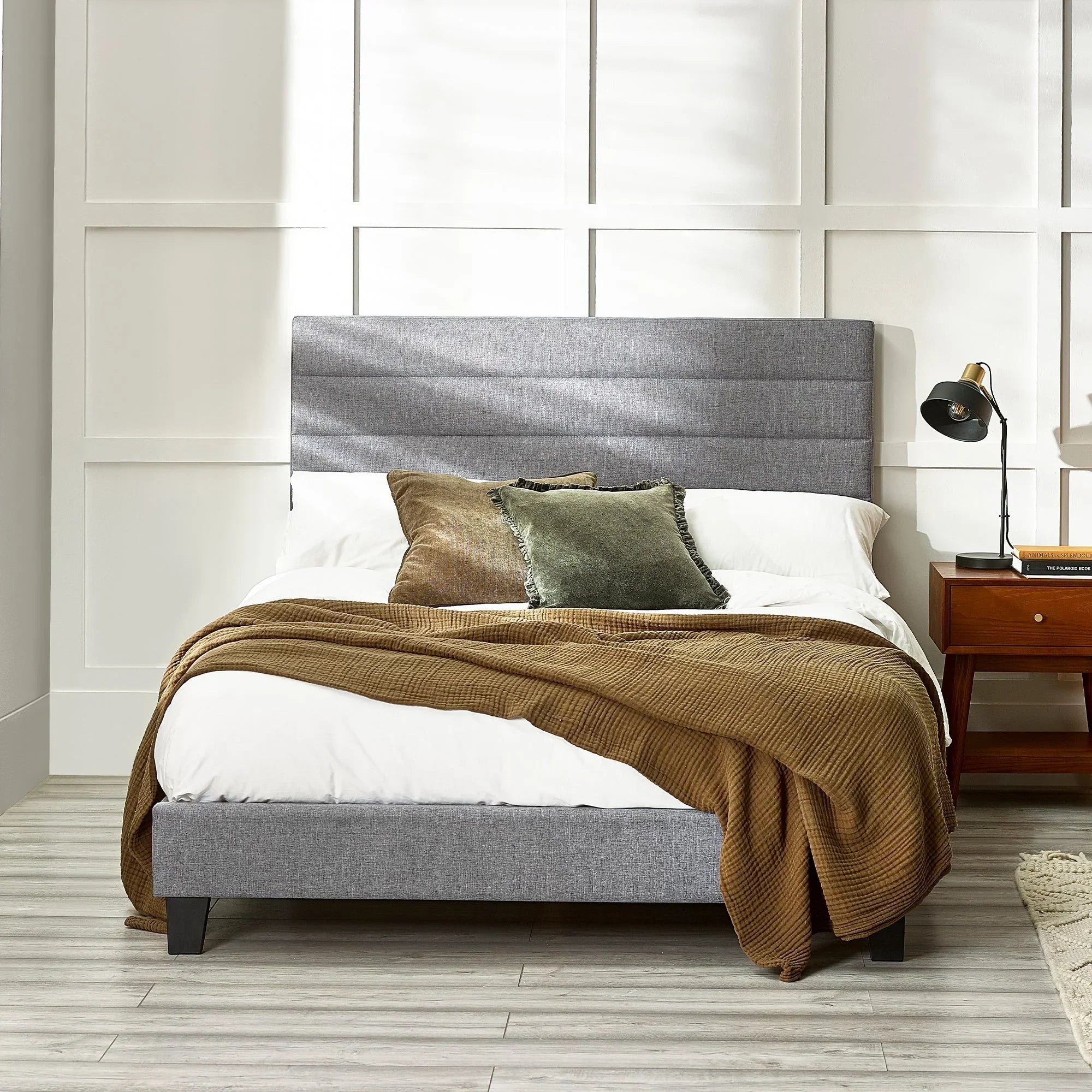 Grey upholstered bed with headboard, brown throw, and cushions in modern bedroom