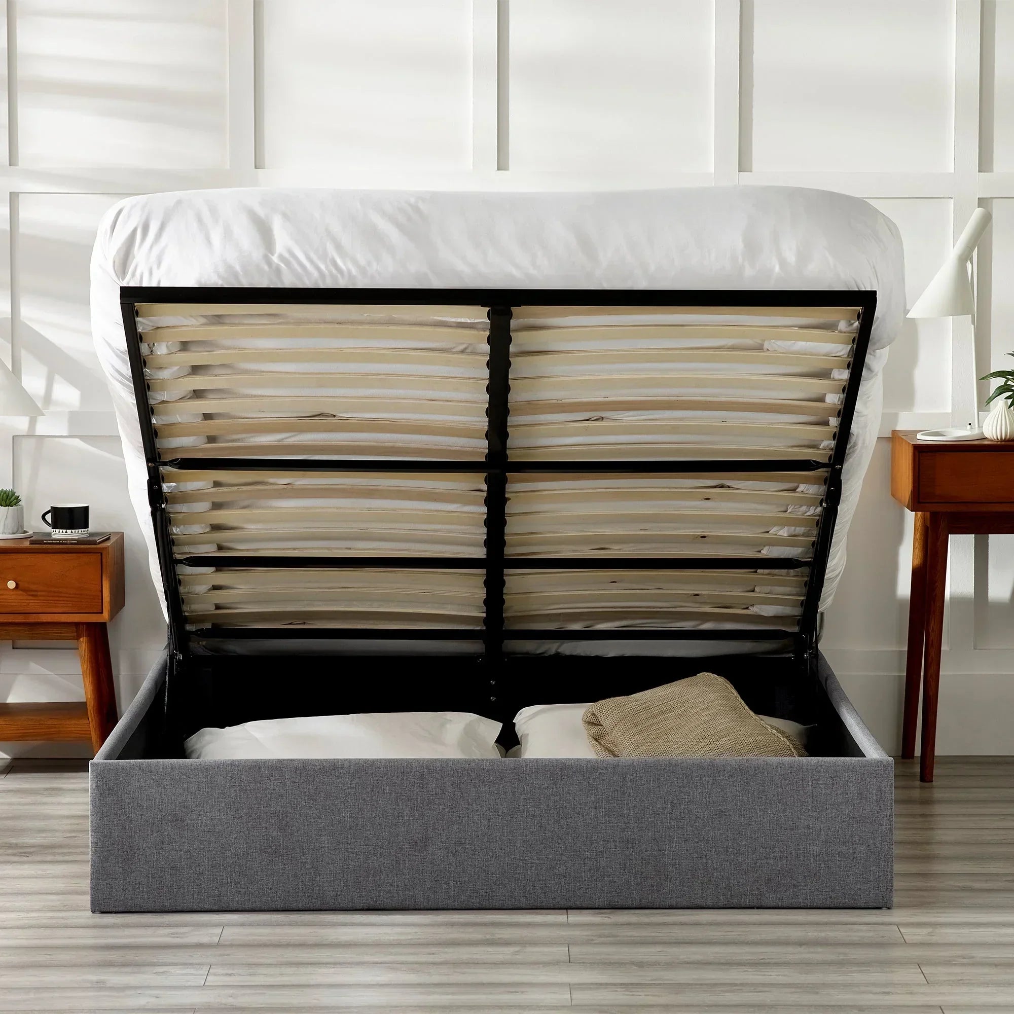 Grey lift-up storage bed with bedding and pillows in modern bedroom setting
