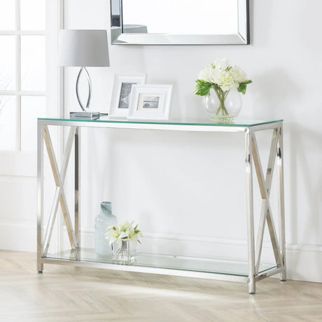 Glass and chrome console table with decorative items and flowers against white wall