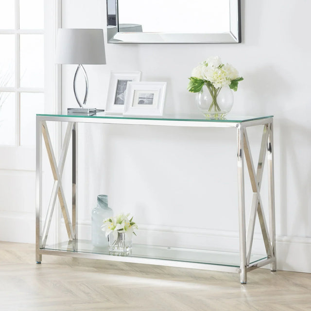 Glass and chrome console table with decorative items and flowers against white wall