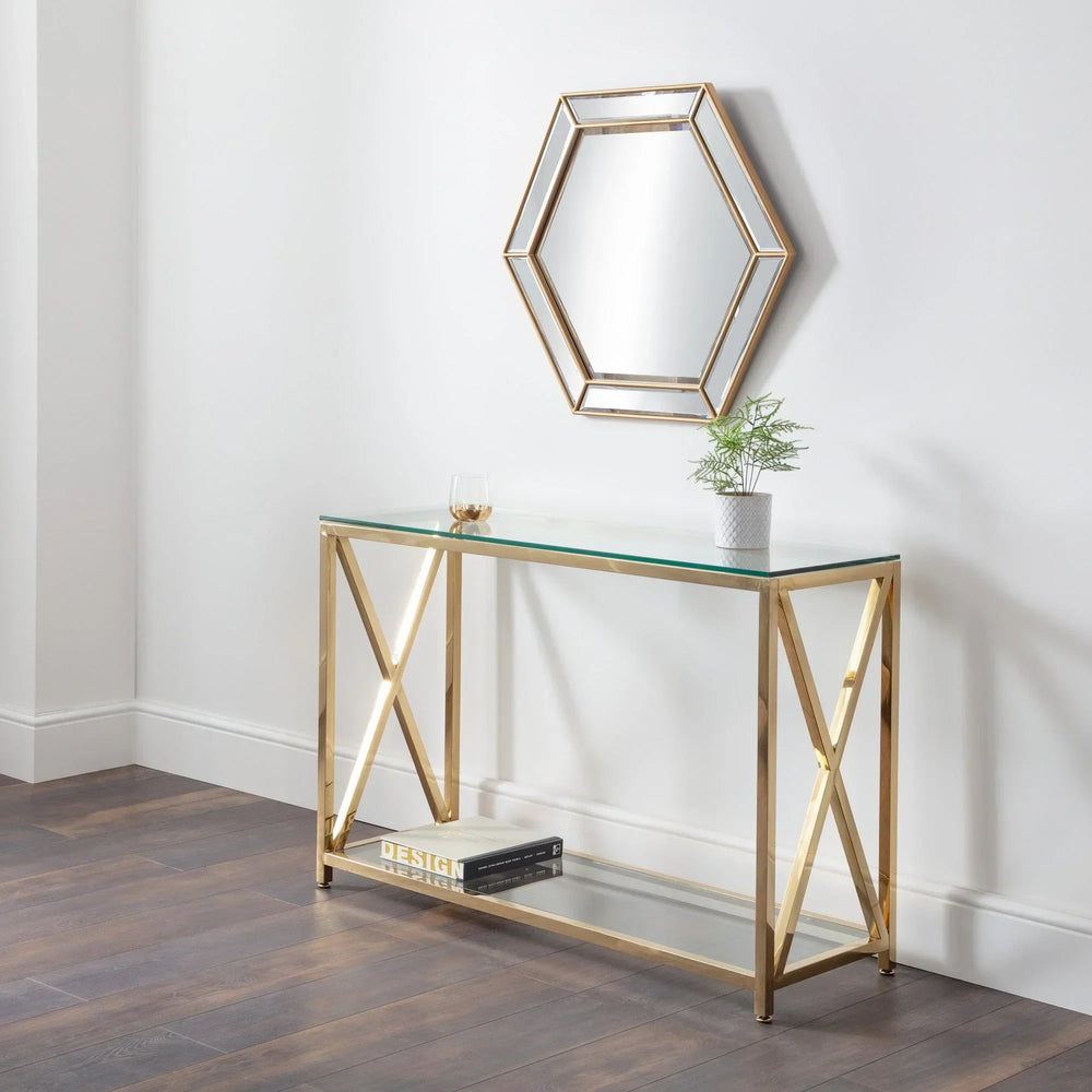 Glass console table with gold metal frame, shelf, and hexagonal wall mirror in hallway