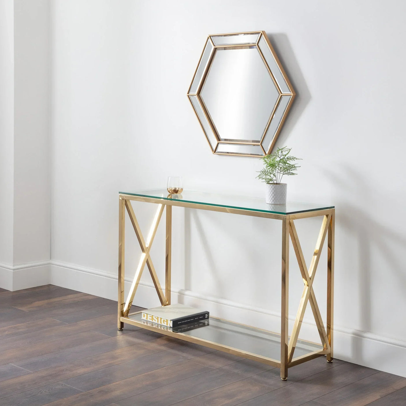 Glass console table with gold metal frame, shelf, and hexagonal wall mirror in hallway