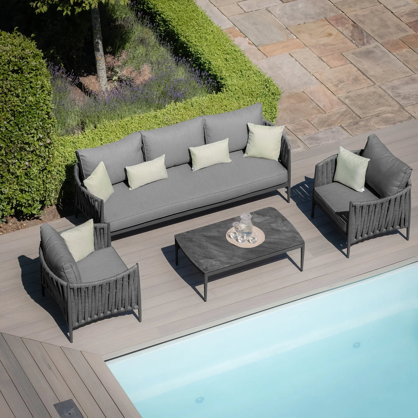 Grey outdoor sofa set with coffee table and cushions by pool on decking