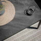 Grey stone-effect coffee table with glass and woven placemat on textured rug