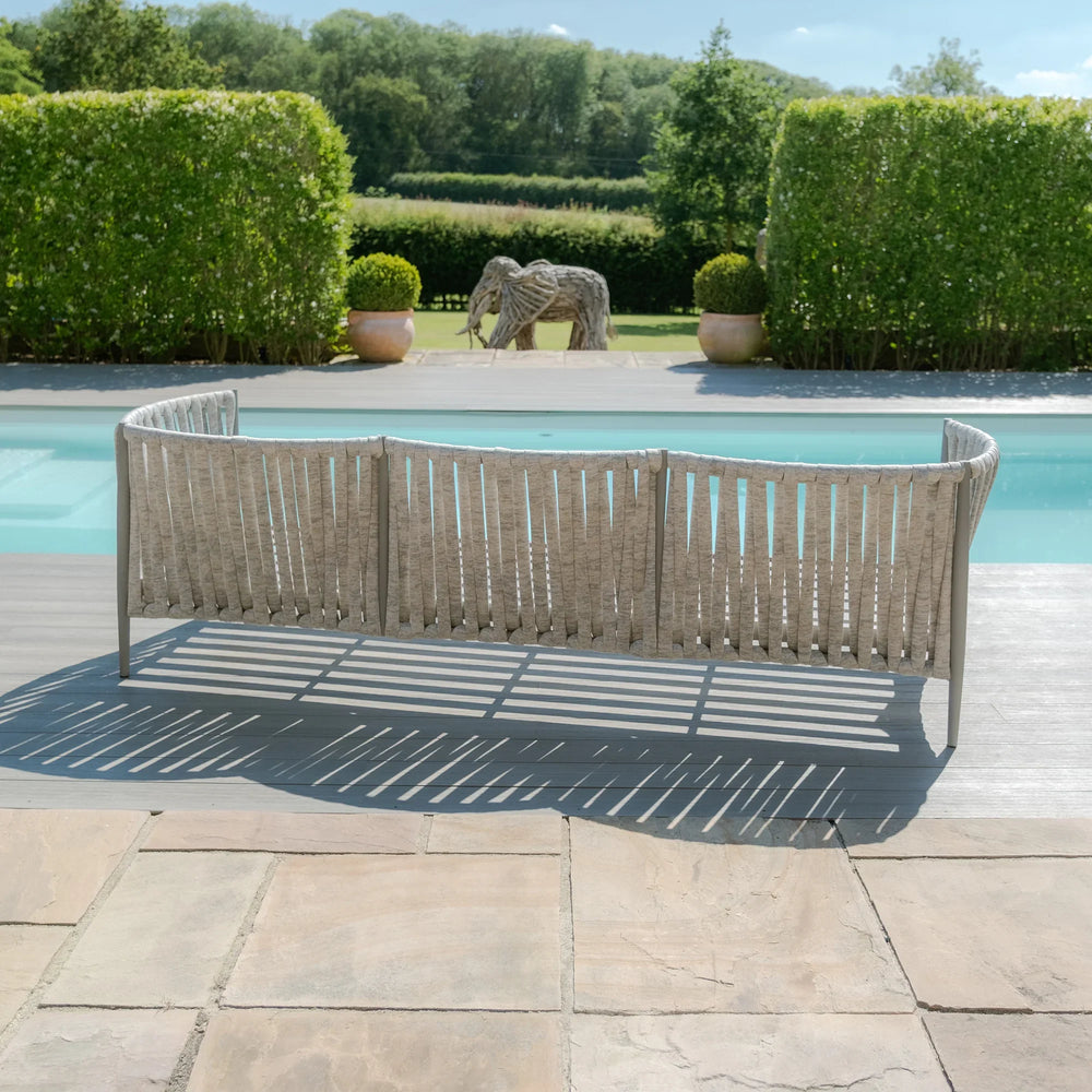 Curved outdoor sofa with woven rope design set by pool on stone patio