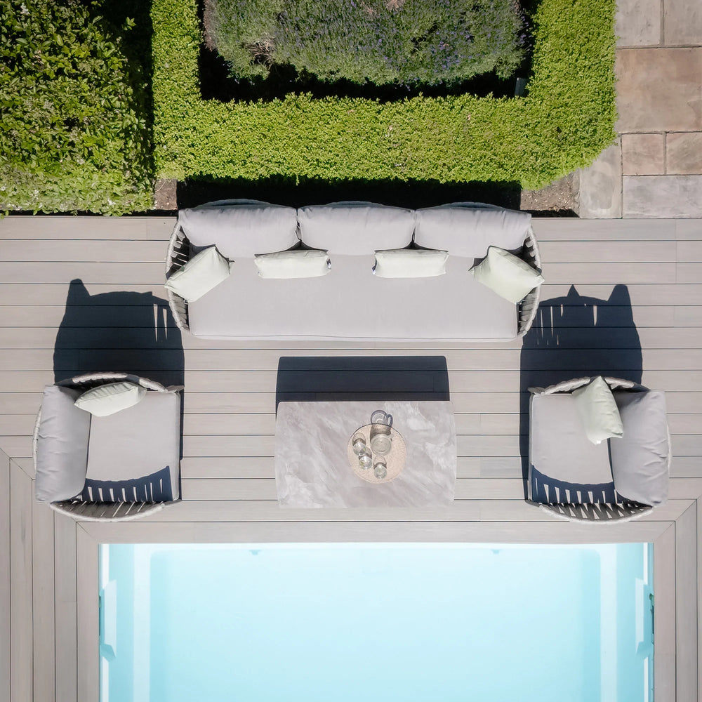 Grey outdoor sofa set with matching chairs and coffee table next to swimming pool on decking