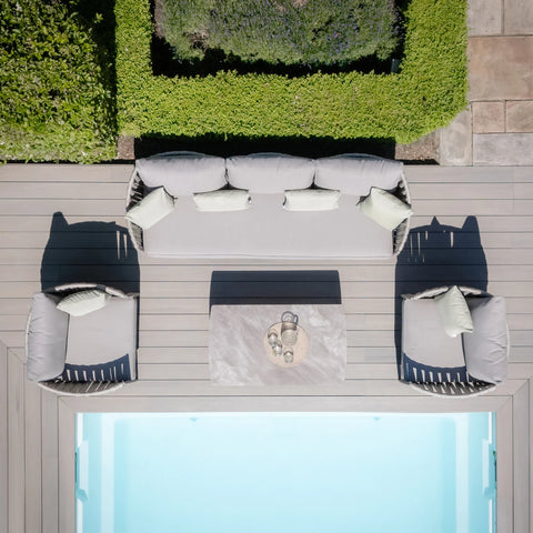 Grey outdoor sofa set with matching chairs and coffee table next to swimming pool on decking