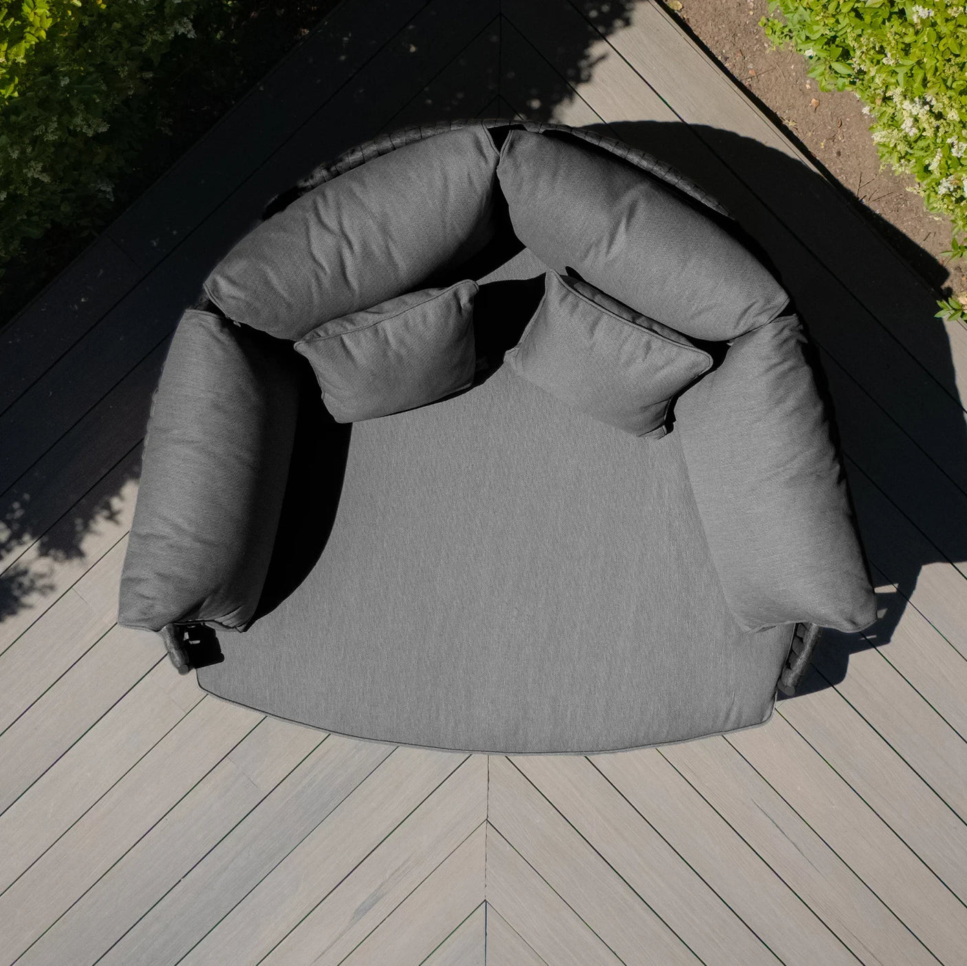 Charcoal grey outdoor daybed with plush cushions on composite deck