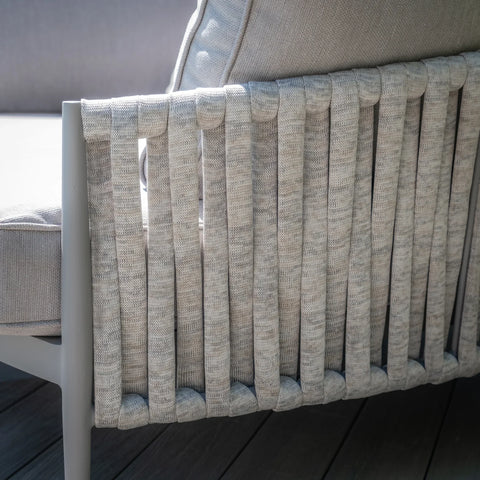 Close-up of woven rope sofa arm detail with light grey cushion on wooden deck