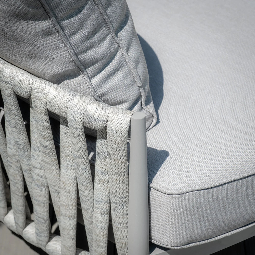 Closeup of woven rope outdoor sofa armrest with light grey cushion and pillow detail
