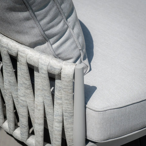 Closeup of woven rope outdoor sofa armrest with light grey cushion and pillow detail