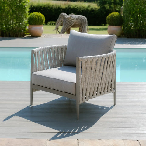 Light grey outdoor armchair with rope detail on poolside decking