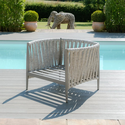 Grey outdoor garden armchair with woven rope design by a pool on wooden decking