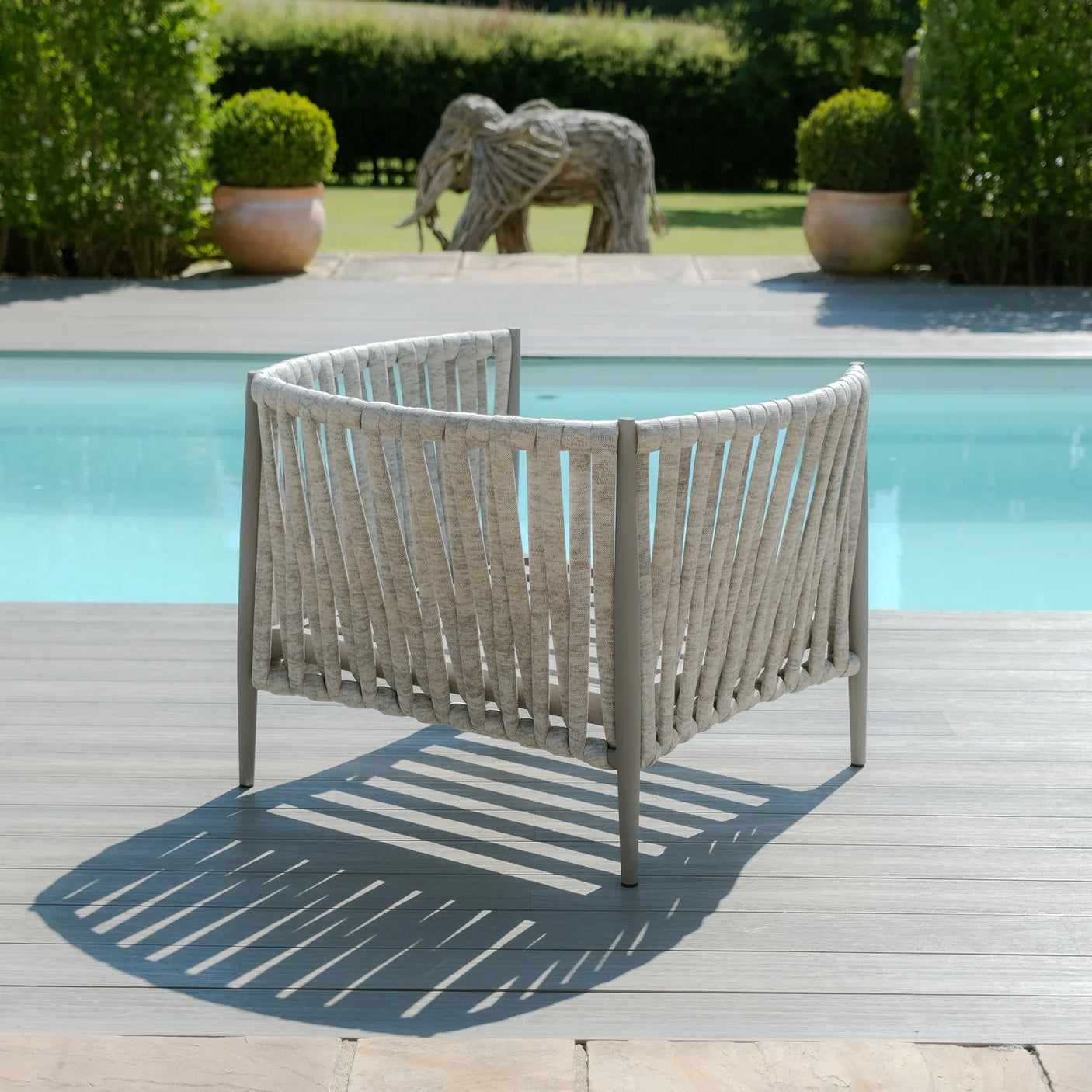 Outdoor rope lounge chair in grey on decking beside a swimming pool