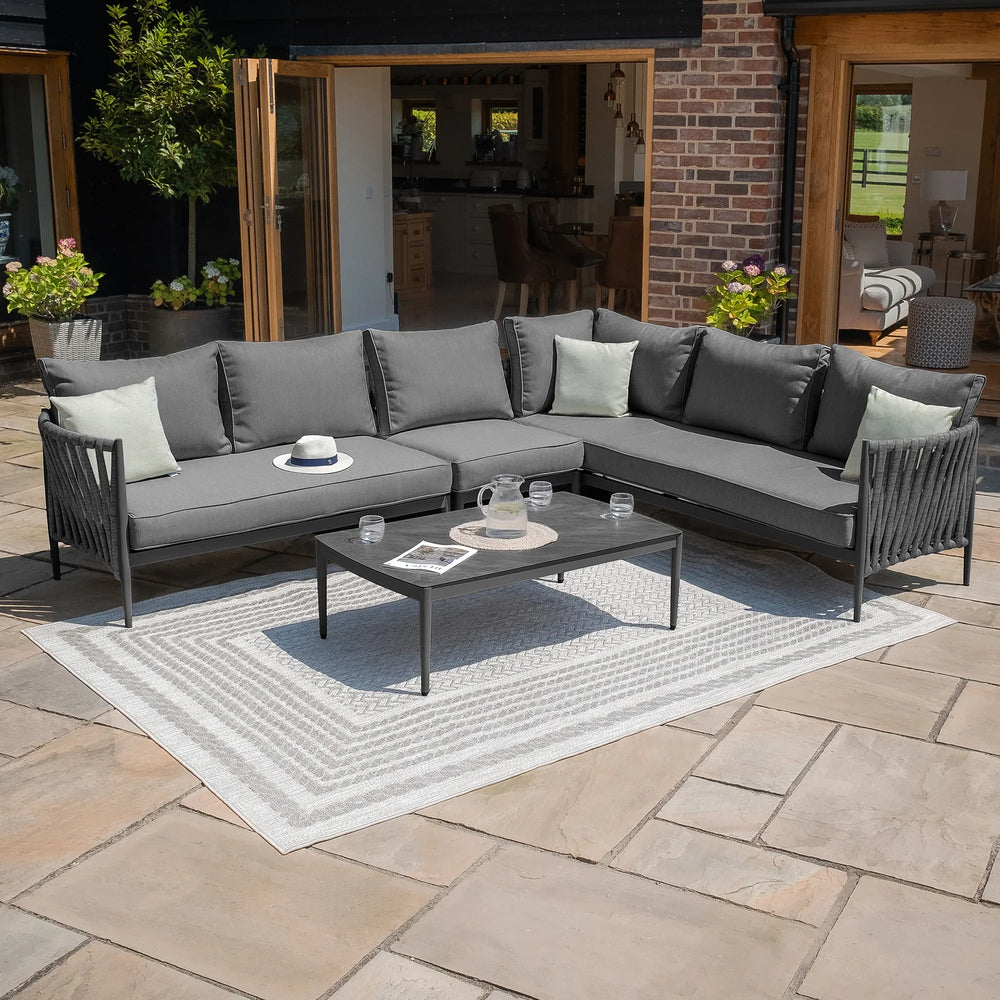 Grey outdoor corner sofa set with cushions and coffee table on patio rug