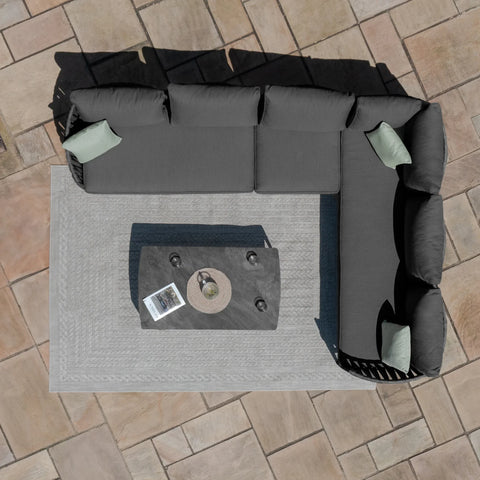 Grey corner outdoor sofa set with cushions and coffee table on patio tiles