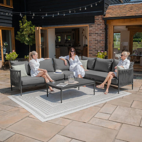 Grey outdoor corner sofa set with black metal frame and coffee table on patio tiles